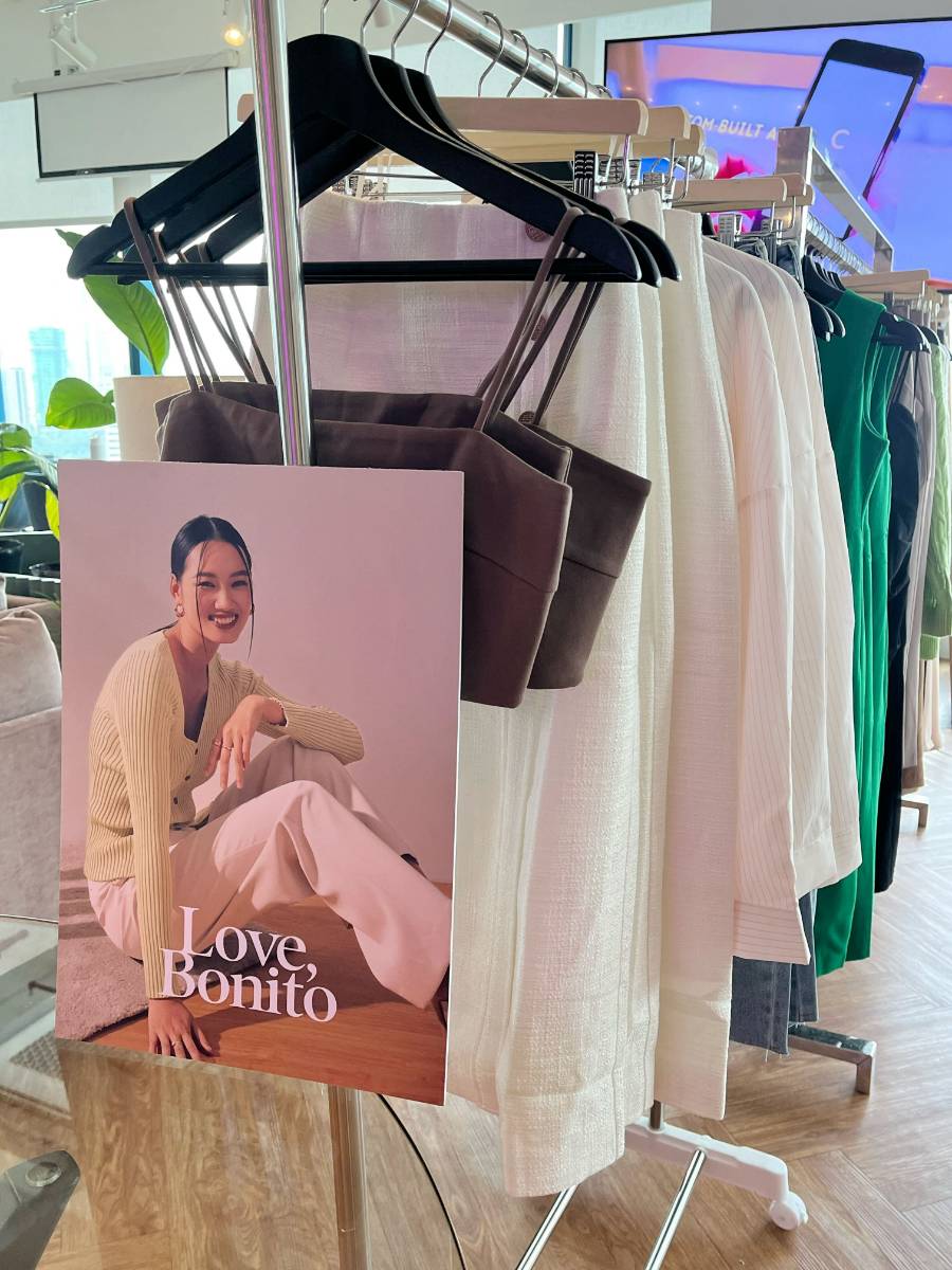 A Love, Bonito sign with a rack of pieces from The Hybrid Wardrobe Collection.