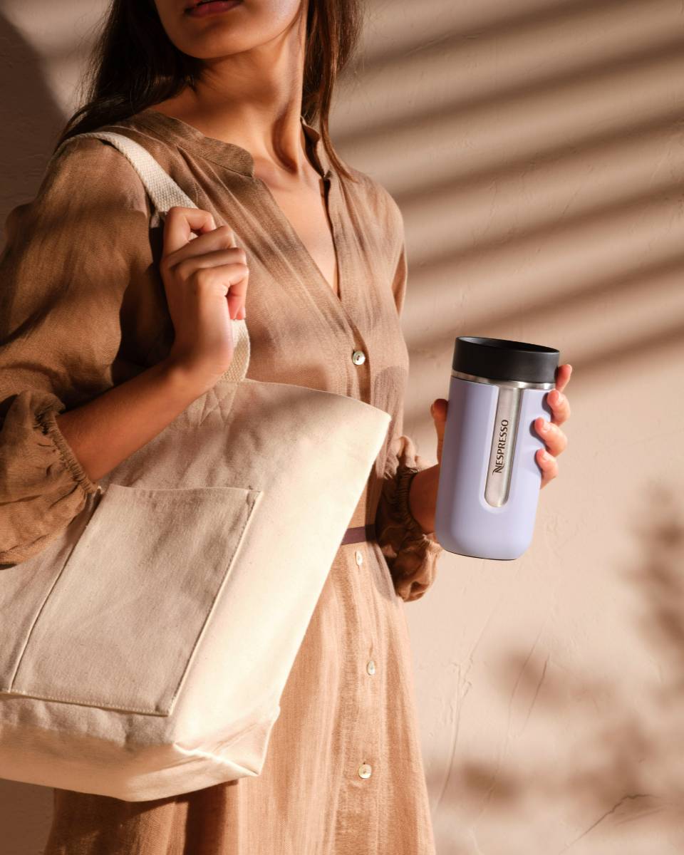 A woman holding the Lavender Nespresso Nomad Travel Mug.